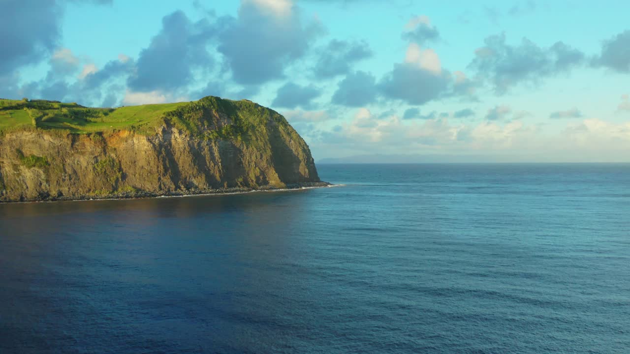 Aerial view of a cliff with the ocean and cloudy sky in Azores
