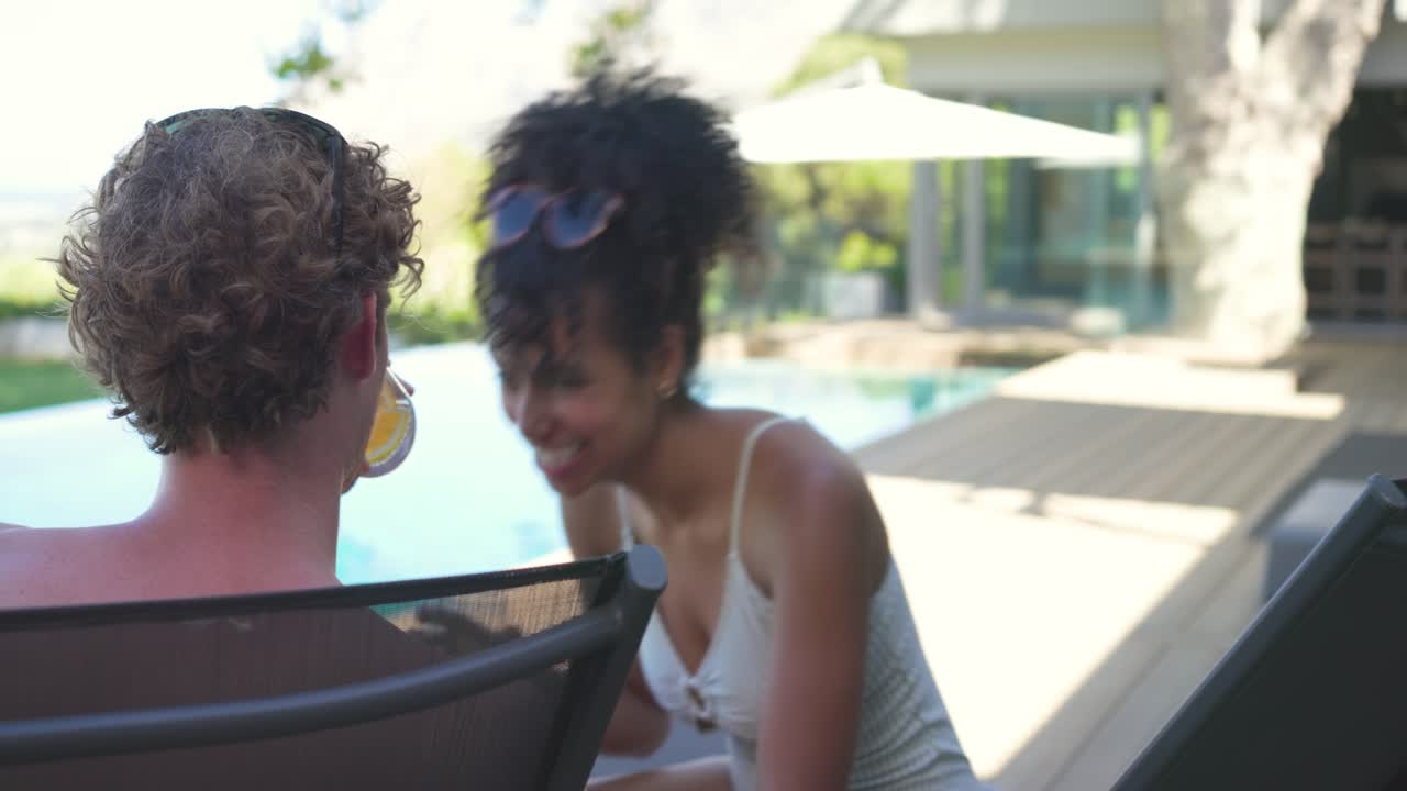 Paar auf Liegen am Pool, die Frau beginnt ein Gespräch, bietet Getränke an, das Paar stößt an, entspannt sich.