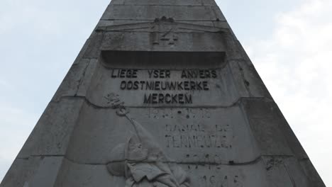 military stone obelisk monument honoring the 14th line regiment in liège, belgium. it showcases engraved inscriptions and relief sculptures in honor of its historical significance.