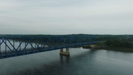 aerial establishing view of the steel bridge over lielupe river on a sunny summer morning, fog rising over the river, cars driving, wide ascending drone shot moving forward