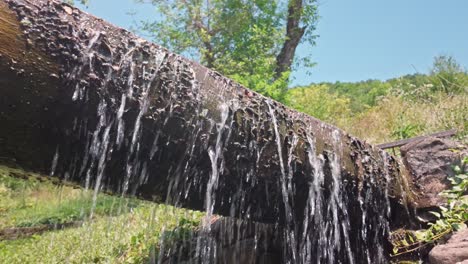 Overflowing-water-cascading-from-rustic-wooden-sluice-log-flume-chute