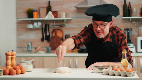 man sieving flour over dough on table
