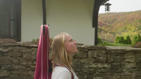 músico femenino camina por el callejón amurallado pueblo rústico admira la vista de otoño