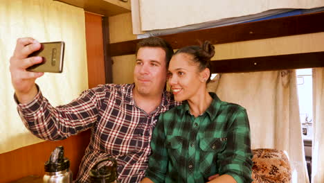 cheerful young couple taking a selfie inside their vintage camper van