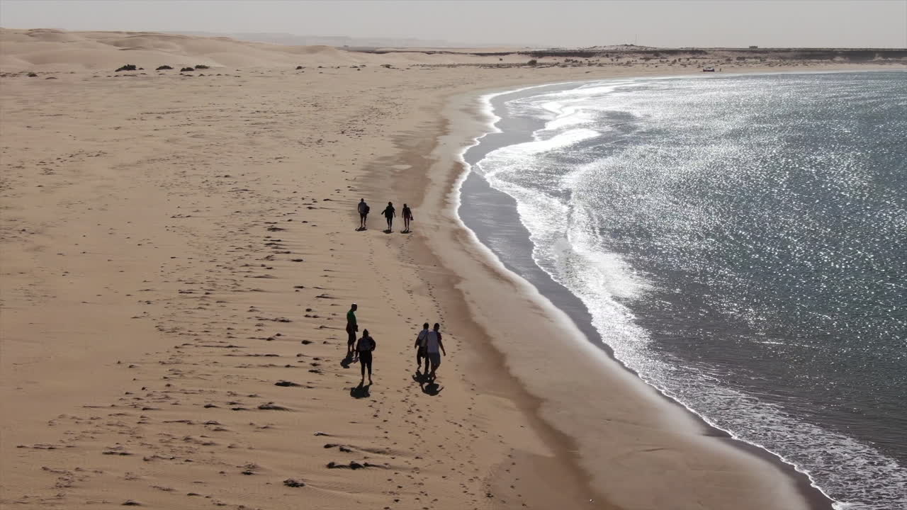 aerial shot of people walking along the shore of the Naila lagoon in Tarfaya, Morocco.