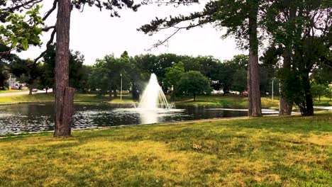 walking up a grassy hill in deering oaks park in portland, maine at the top a view of duck pond and fountain.  4k