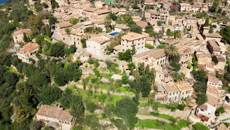 dramatic aerial top down flyover of deia mallorca with old church and buildings