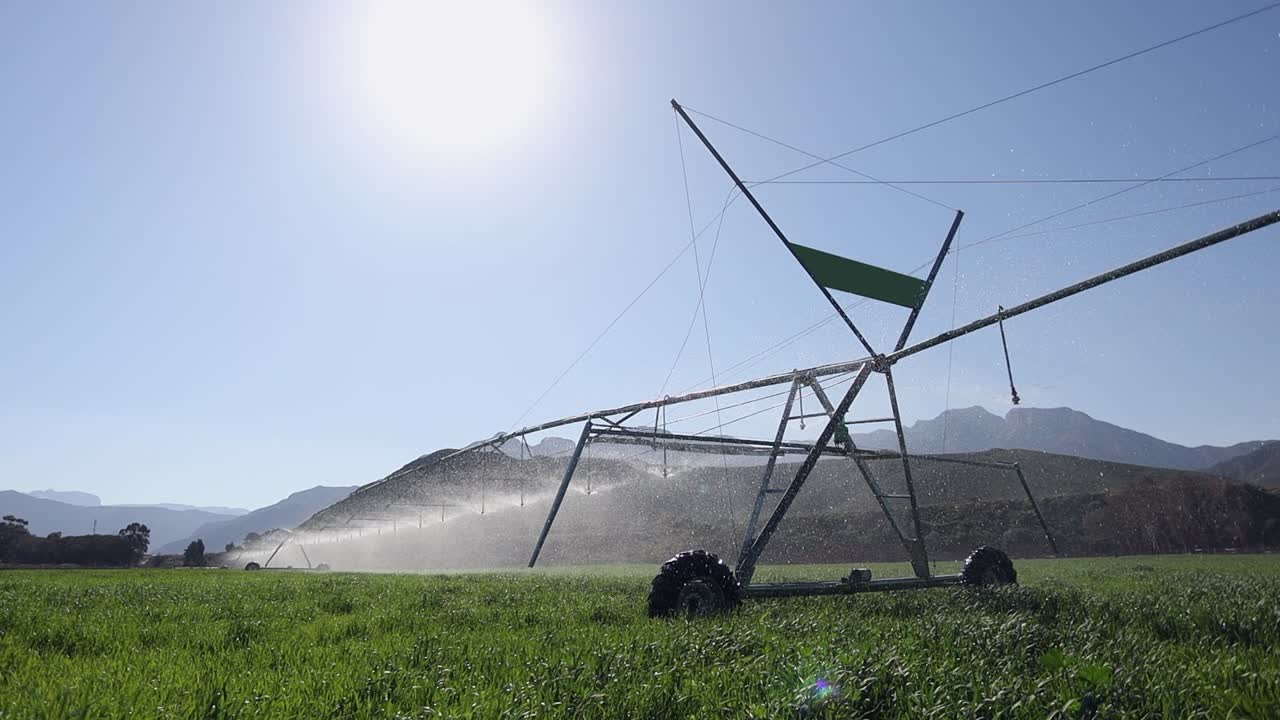 Low angle big sky sun back lights water spray from irrigation pivot