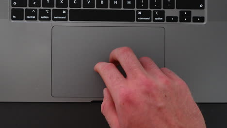 a laptop user is moving the arrow on the screen with his fingers on the tactile trackpad