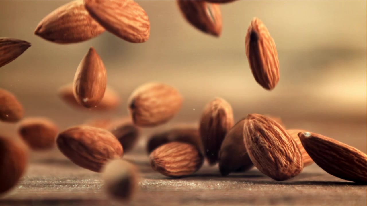 Des amandes tombant au ralenti sur une surface en bois.
