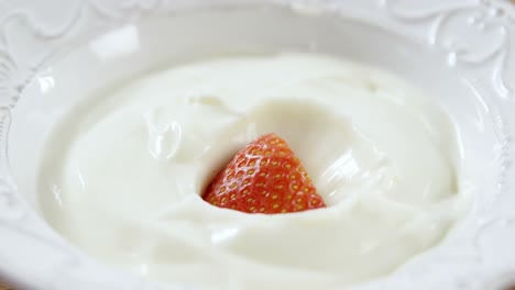 Strawberry falling in whipped cream