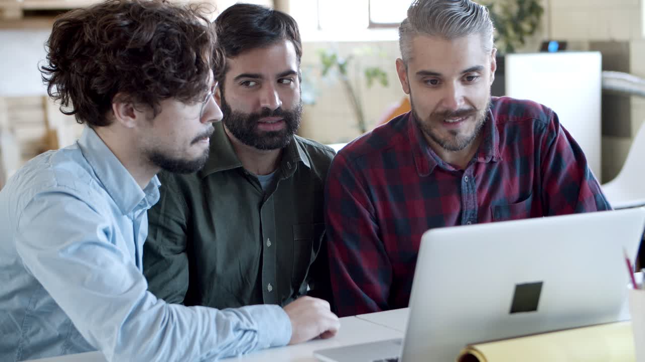 Focused young people sitting at table and looking at laptop