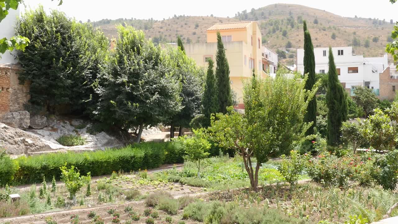 Jardín nazarí con parcelas cultivadas, plantas aromáticas y cipreses con las casas de Vélez de Benaudalla