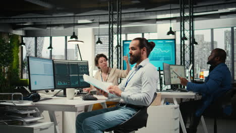 vertical video office employee reviewing kpi metrics on monitor and analytics on files