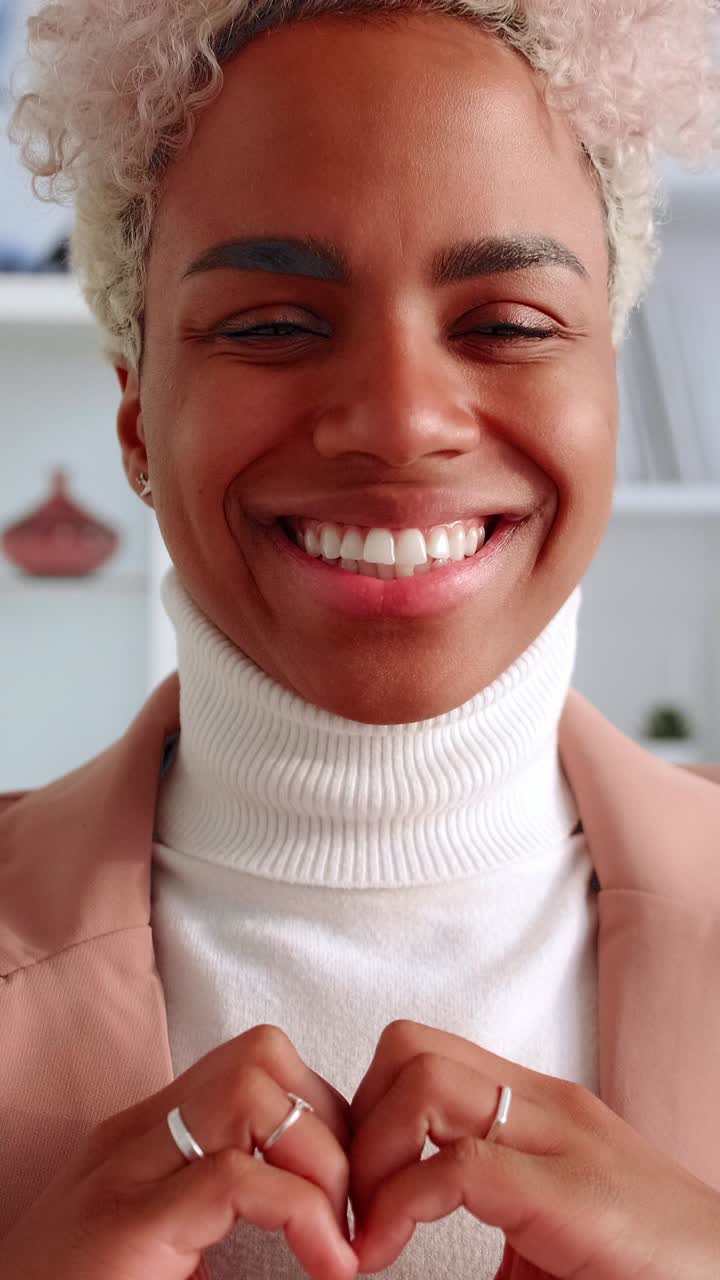 Smiling young woman making heart gesture with hands in a closeup portrait