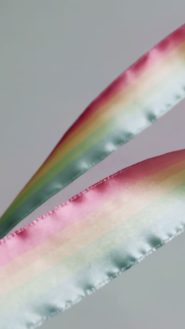 Vertical video: Blowing breeze sending two satin ribbons twisting across studio with stitched edges
