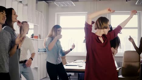 happy european woman leader dancing at office party. multiethnic colleagues enjoy fun bonding time activity together 4k