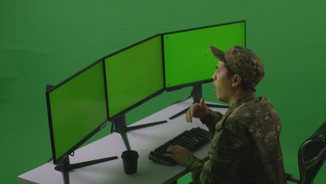 side view of tired asian man soldier yawning before sleeping while working with mock up multiple computer monitor in green screen studio