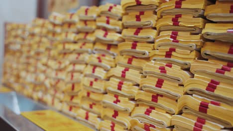 stacks of folded yellow joss paper with red bindings neatly arranged at ciyou temple in taiwan taipei, ready to be burned as spiritual offerings in a traditional ritual honoring ancestors and deities