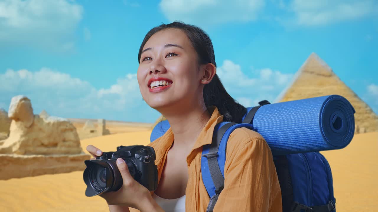 Close Up Side View Of Asian Female Hiker With Mountaineering Backpack Smiling And Holding A Camera In Her Hands Then Looking Around While Traveling In Pyramid Of Giza