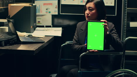 el usuario de silla de ruedas del detective sostiene el diseño de pantalla verde en la tableta