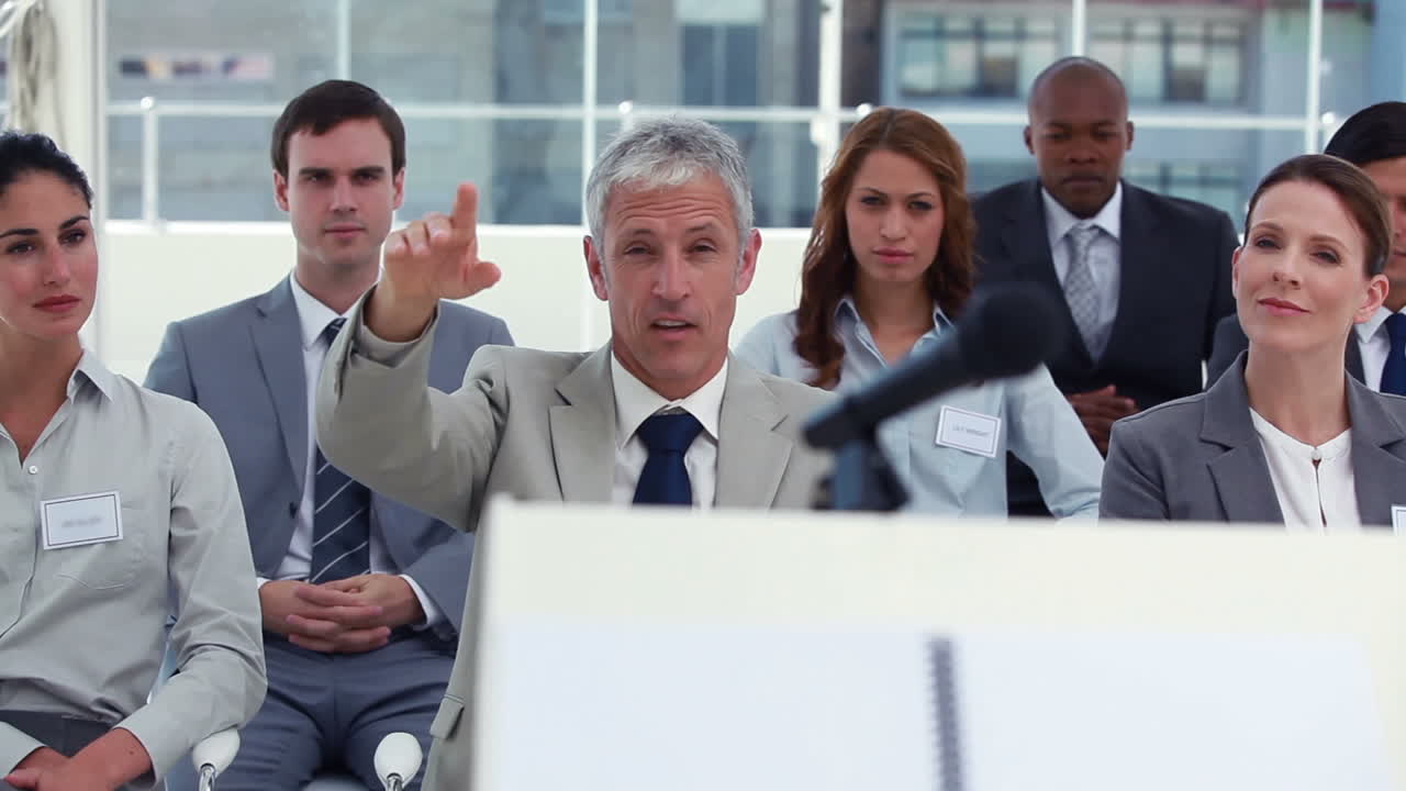 회색 머리카락의 남자가 질문을 하고 있습니다.