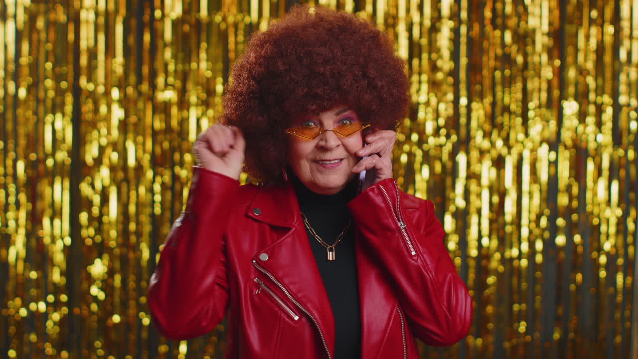 Cheerful one woman in jacket looking at camera doing phone gesture like says hey you call me back