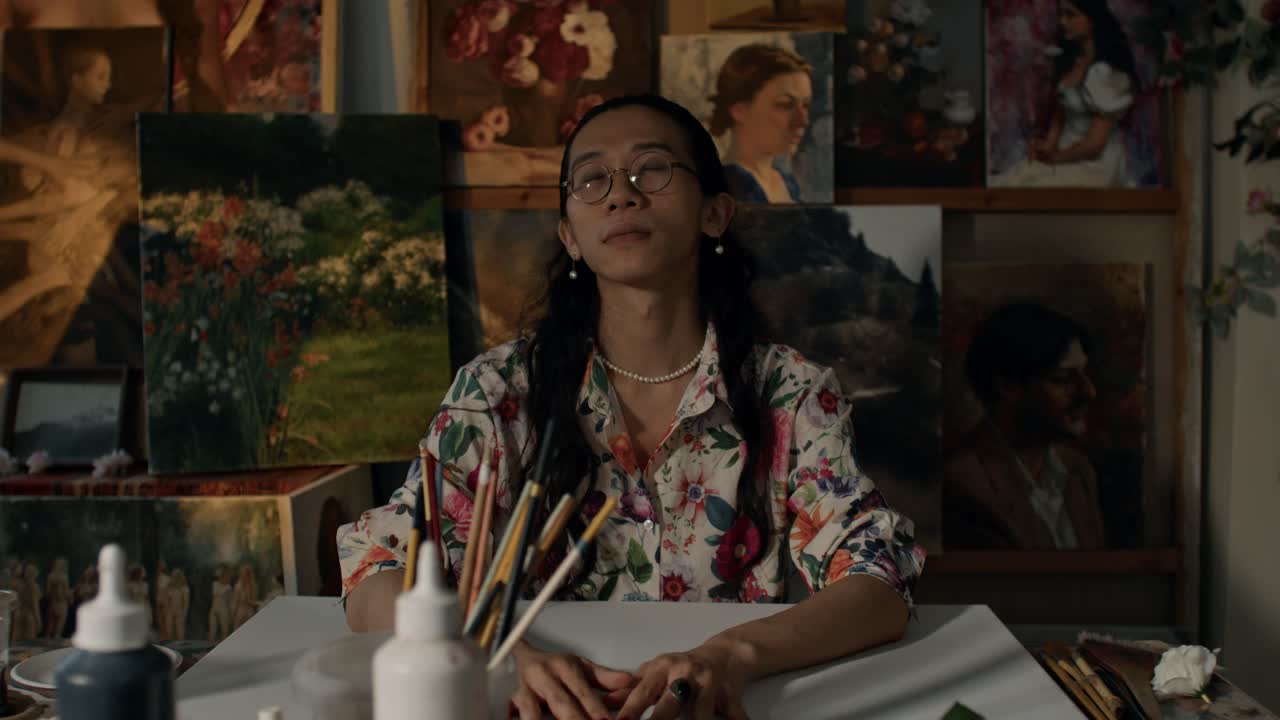 Artist in Studio with Paintings and Flowers