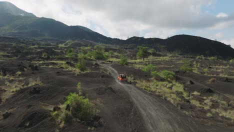 all wheel drive jeep traveling through black sand volcanic landscape below volcano