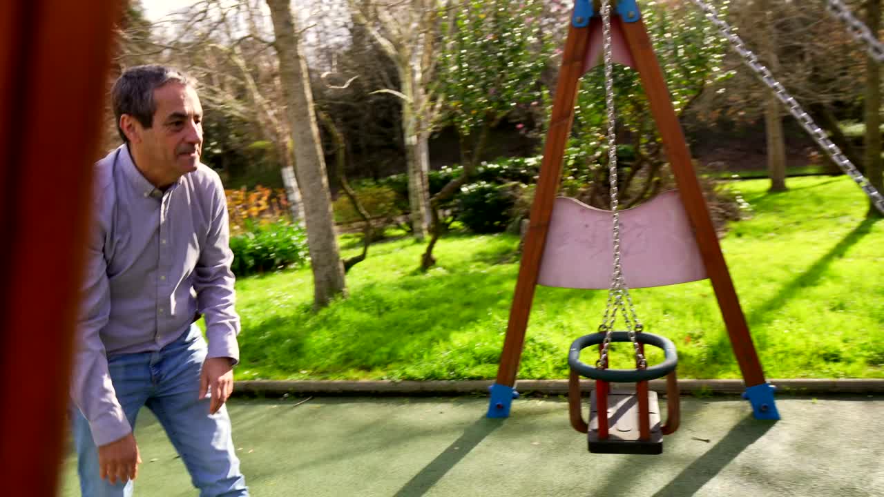 Father and Son Playing on a Swing at the Playground
