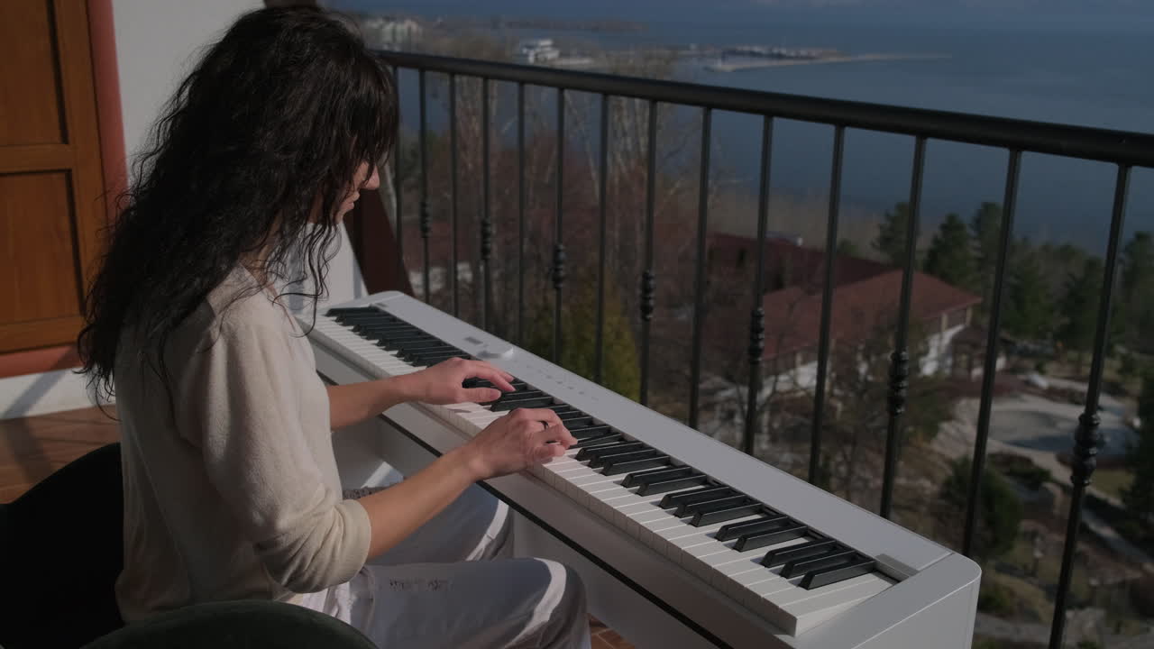 mujer tocando el piano en un balcón con vistas al lago