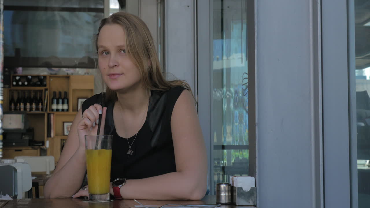 mujer con mirada melancólica tomando jugo en el café