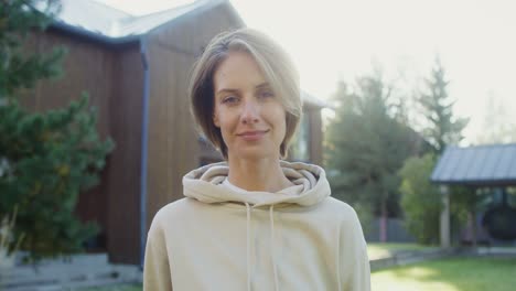 woman in a hoodie in front of a house