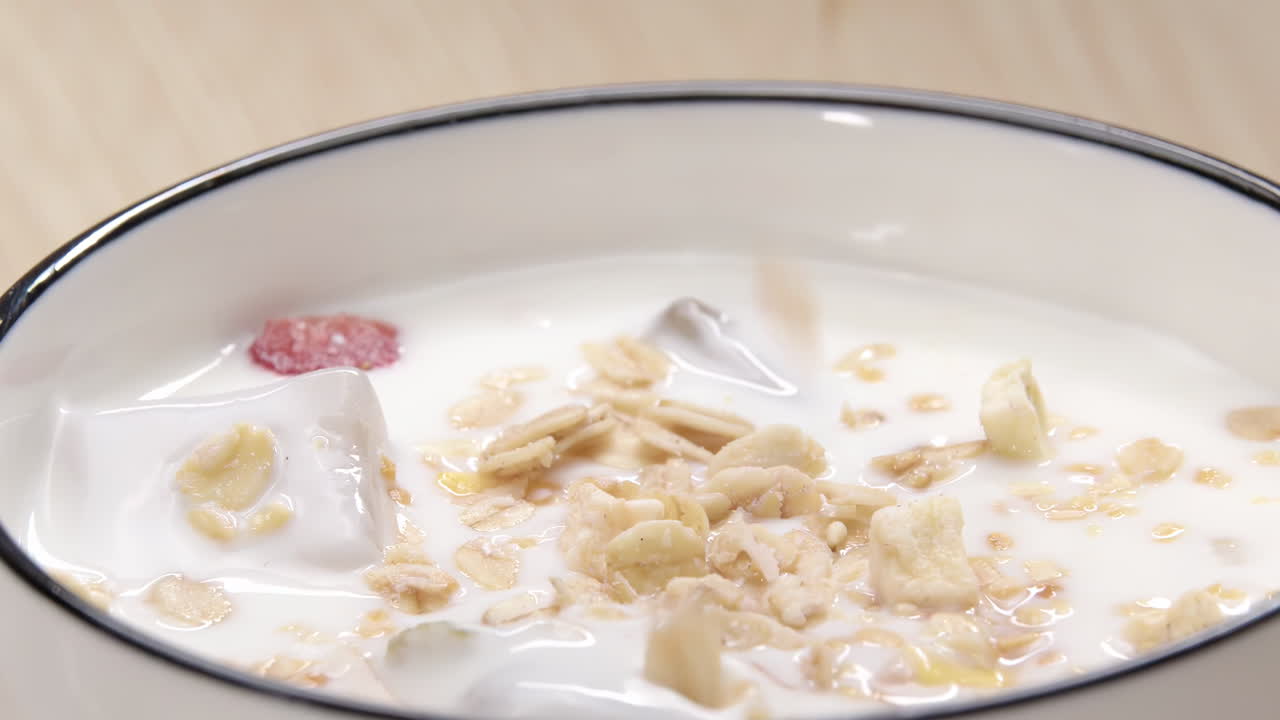 Scena di colazione sana con aggiunta di mandorle tritate o scaglie di cocco a cereali mattutini colorati a forma di stella a base di yogurt naturale con l'aggiunta di semi di zucca, perfetto per spot pubblicitari alimentari.
