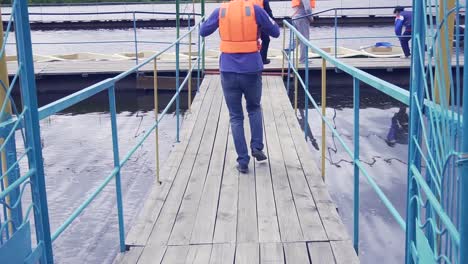 people wearing life jackets on a wooden dock by the water