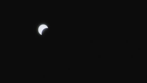 sun partially covered by moon against dark sky during solar eclipse