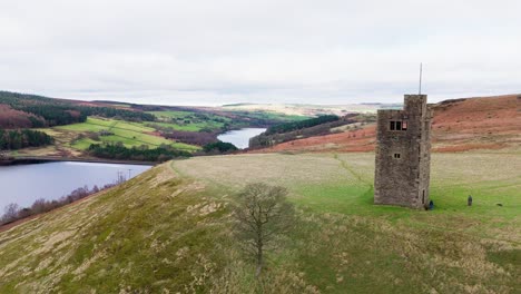 Old-derelict-castle,-monument,-disused-stone-tower,-with-people-walking-around-and-flying-a-drone