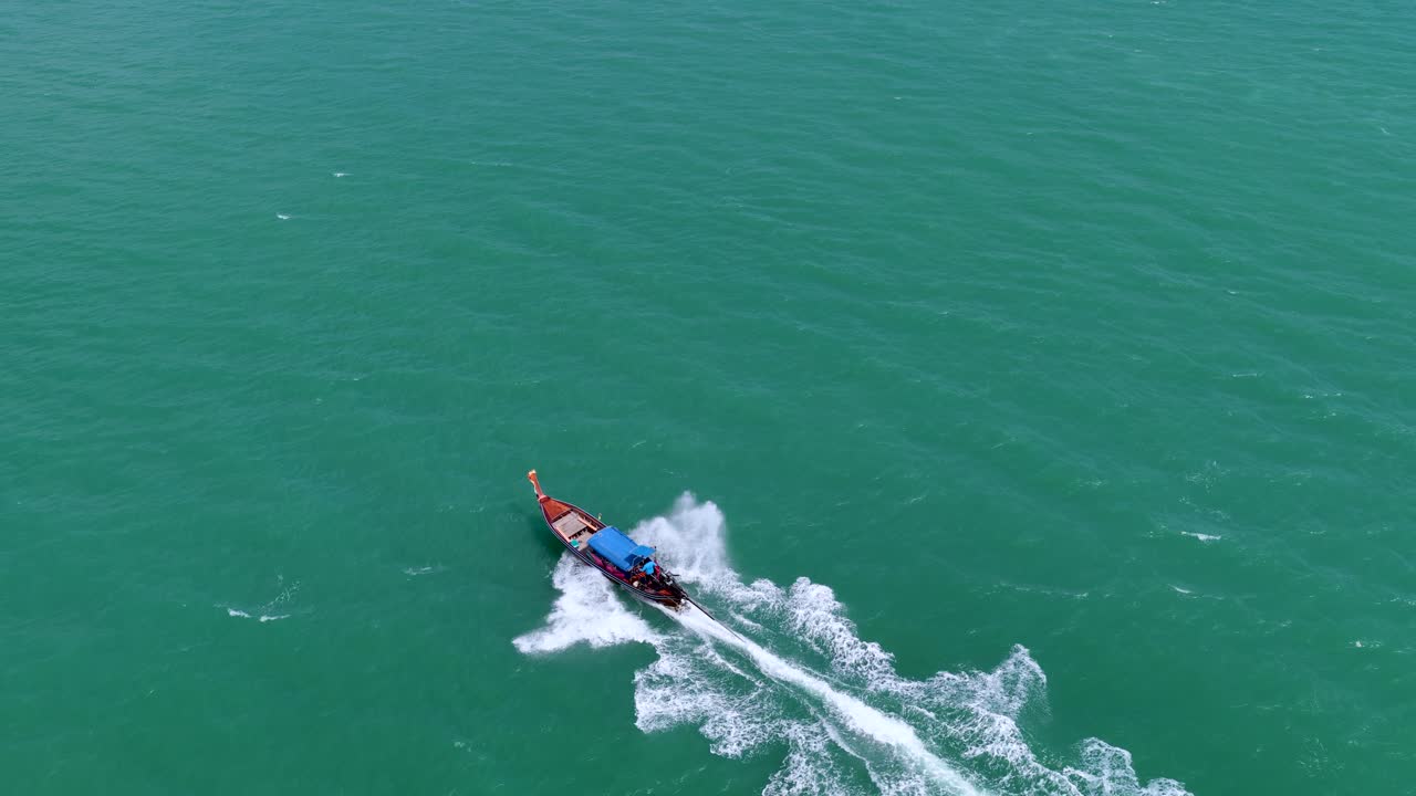 Bidikan udara sudut tinggi perahu ekor panjang tradisional menciptakan jejak busa putih di Krabi