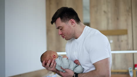 happy new-made father dandling his newborn baby in hands. father and son moment in maternity hospital.
