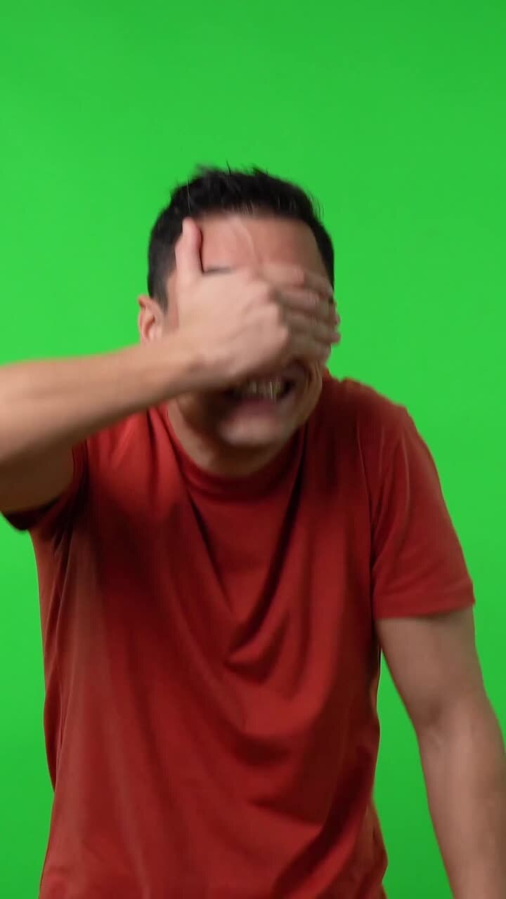 Man covering eyes on green screen