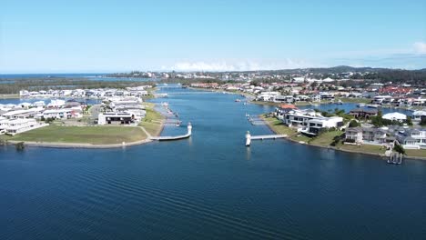 aerial view of a riverside residential area with modern houses lining the waterway. the serene waterfront community offers peaceful surroundings with boats docked along the shore