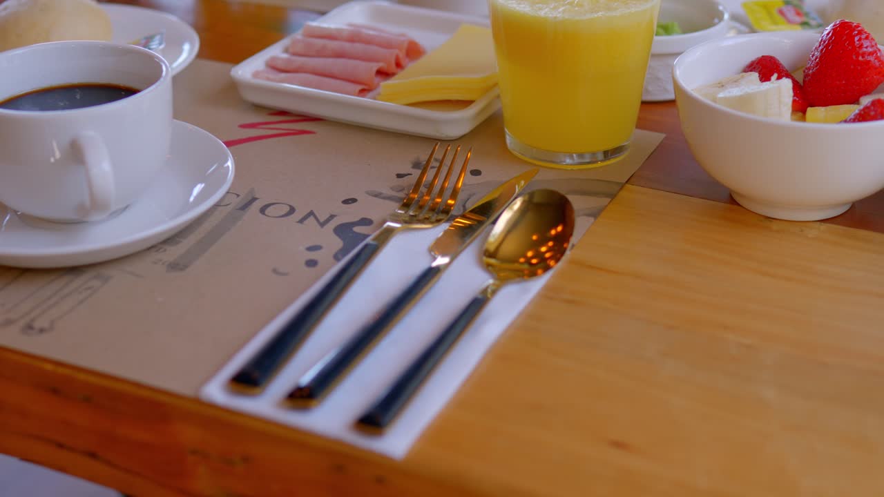 mesa con desayuno servido, cuchillo, cuchara y tenedor de color bronce con elegante negro resaltan