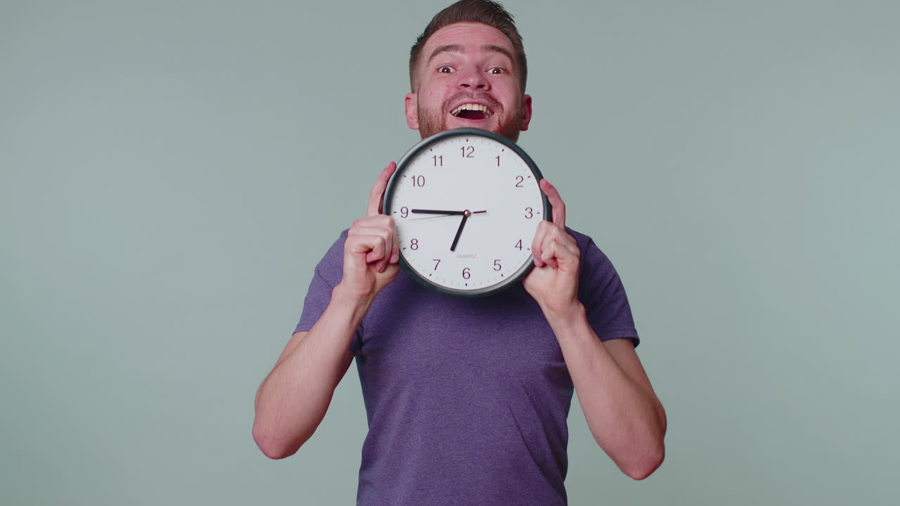 joven con un reloj de reloj, escondiéndose, comprobando la hora en el reloj, llegando tarde al trabajo estando atrasado
