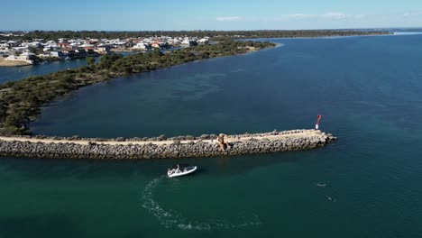 Luftstoß-Einer-Frau,-Die-Von-Einem-Boot-Springt-Und-Neben-Der-Halbinsel-Schwimmt