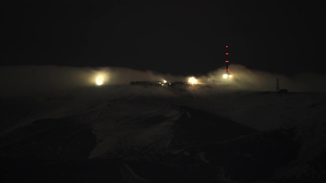 Torri di comunicazione su una cima di montagna innevata di notte nella nebbia