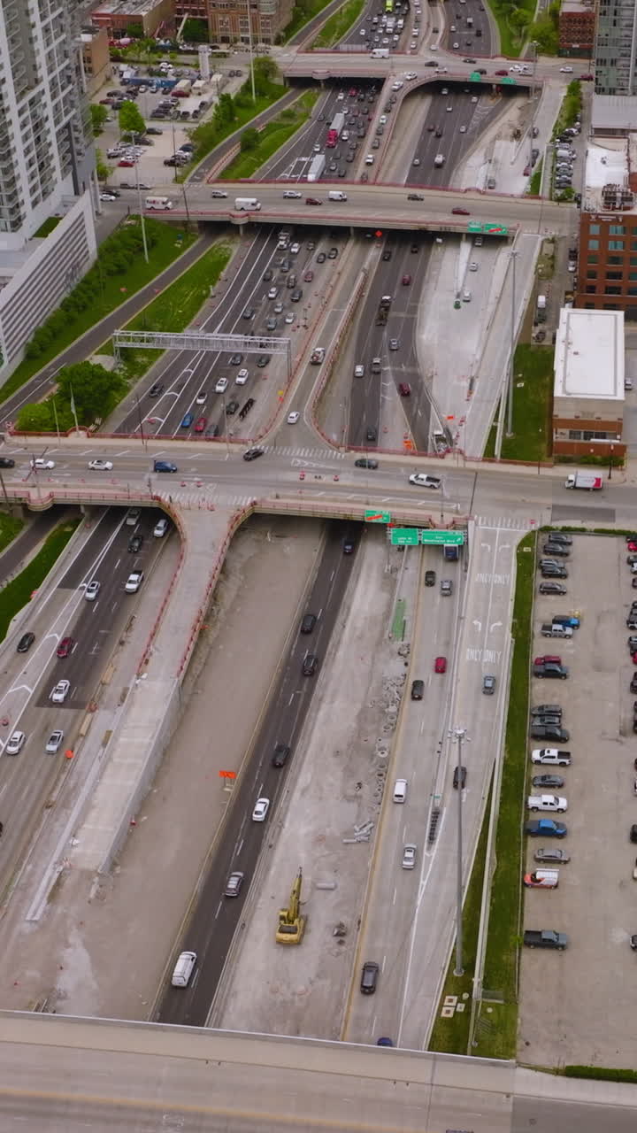 Hundreds of cars on the roads and parking lots of amazing Chicago. Wide multi-lane road crossed by bridges of skyways. Top view. Vertical video