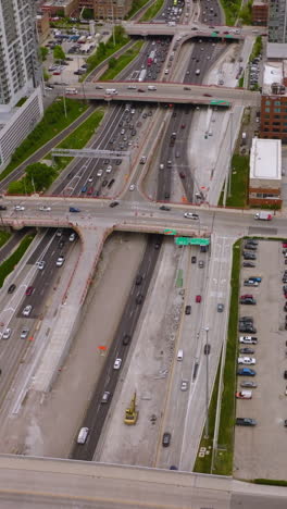 hundreds of cars on the roads and parking lots of amazing chicago. wide multi-lane road crossed by bridges of skyways. top view. vertical video