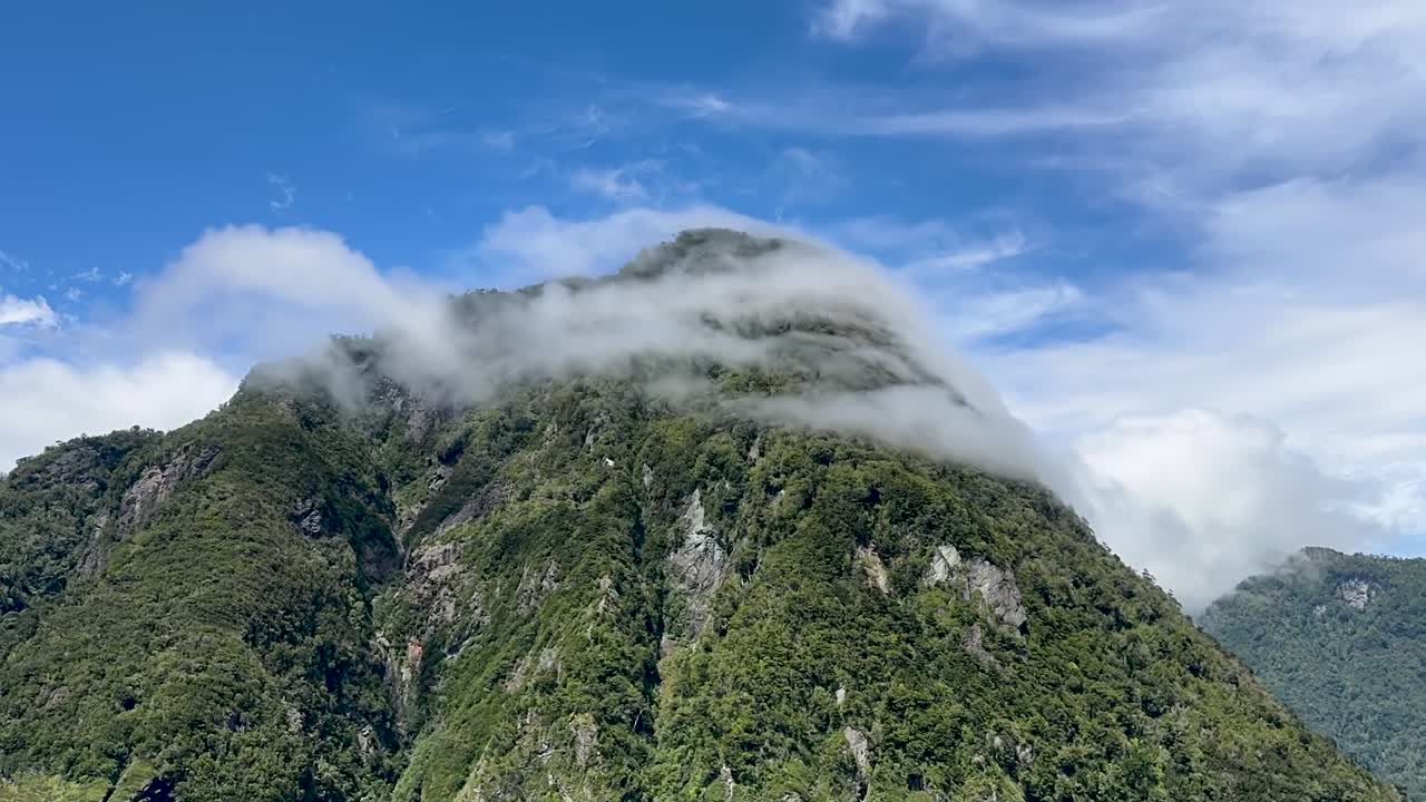 Time-lapse a mano dal ponte di un traghetto sulla Carretera Austral, che mostra nuvole in rapido movimento sopra montagne nebbiose e fiordi nella Patagonia cilena.