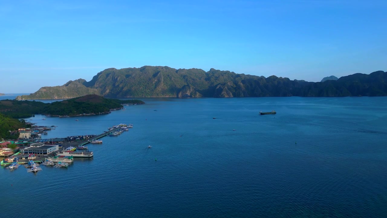 Paisaje sereno desde arriba mostrando barcos en las aguas cristalinas de la Bahía de Coron, Palawan, rodeada de exuberantes islas tropicales. Bonito panorama de dron con vista aérea ascendente.