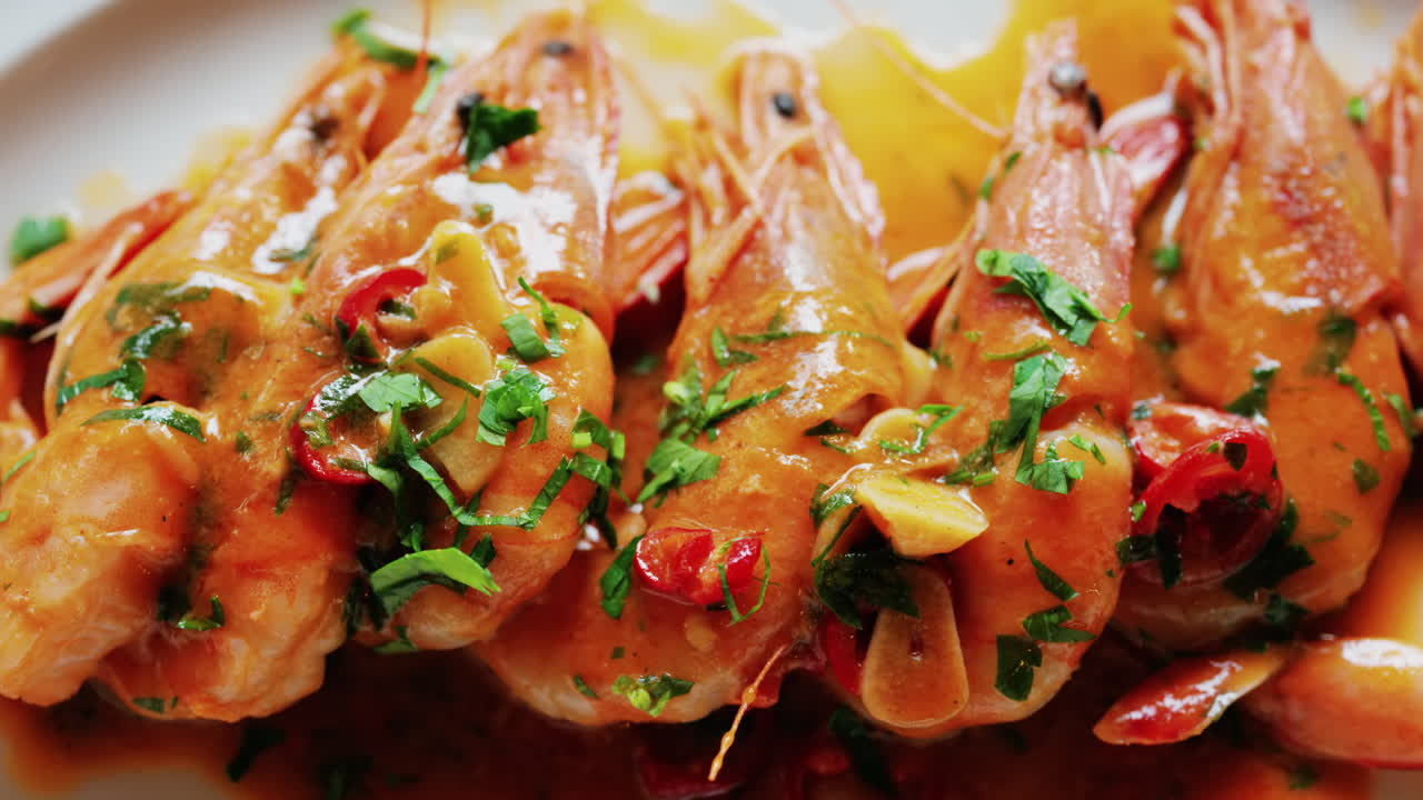Garlic prawns in a rich sauce topped with herbs on a white plate
